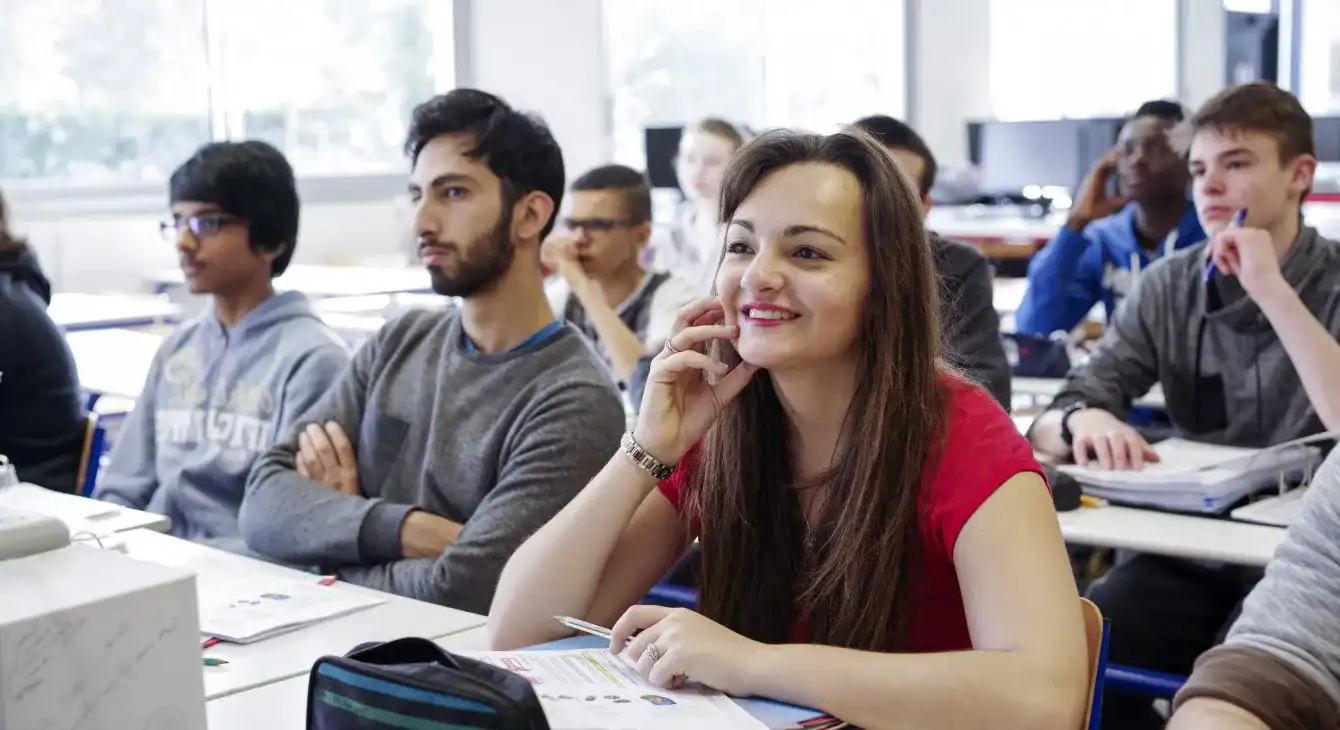 Engaged higher education students participating in a classroom lesson, focusing on a smiling young woman.